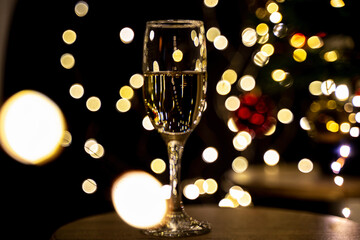 a glass of champagne on a dark background with garland lights

