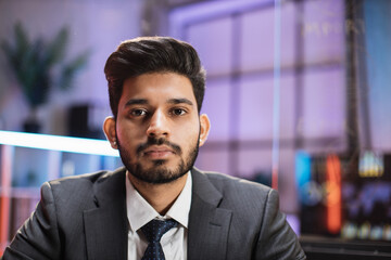 Fototapeta premium Portrait of confident arab man in formal wear sitting at office desk. Company worker with beard looking at camera. Concept of people and business.