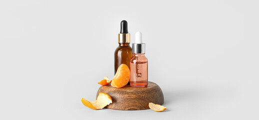 Bottles with tangerine essential oil on light background - obrazy, fototapety, plakaty