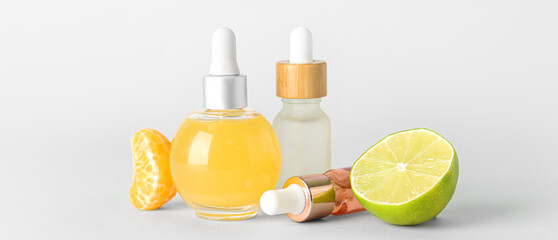 Bottles of citrus essential oil on light background