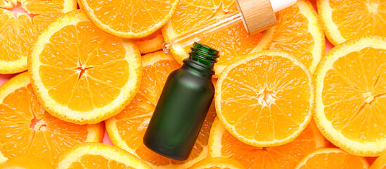 Bottle of citrus essential oil on orange slices, top view