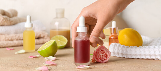Female hand putting bottle of citrus essential oil on table, closeup