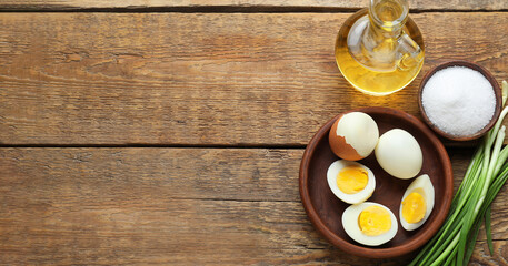 Boiled chicken eggs, oil, salt and green onion on wooden background with space for text, top view