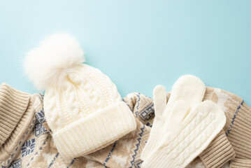 Fototapeta na wymiar Winter concept. Top view photo of white knitted mittens bobble hat and warm sweater on isolated light blue background