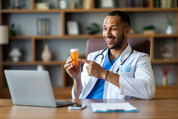 Friendly black doctor working online, having video chat with patient