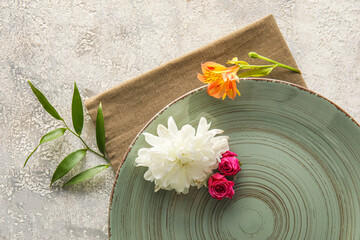 Plate, napkin and beautiful flowers on grey background