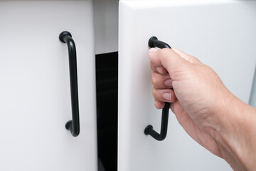 Female hand open white kitchen cabinet,cupboard doors, close up