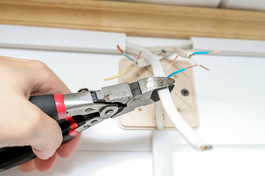 Electrician use of the stripper cutter tool to strip the end of the electrical wire when repairing and updating wiring in the home grid. Electric installation work