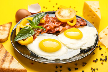 Plate with tasty fried eggs and bacon on yellow background, closeup