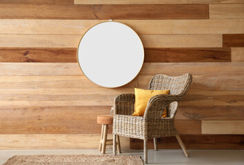 Wicker armchair, stool and mirror hanging on wooden wall