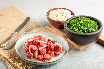 Sliced sausage with onion, green cabbage and farofa.