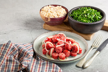 Sliced sausage with onion, green cabbage and farofa.