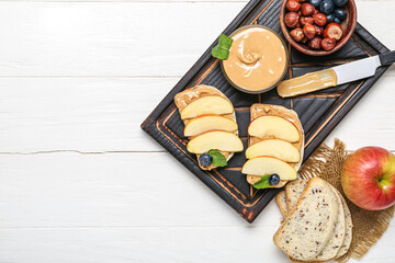 Board of tasty sandwiches with nut butter and apples on light wooden background