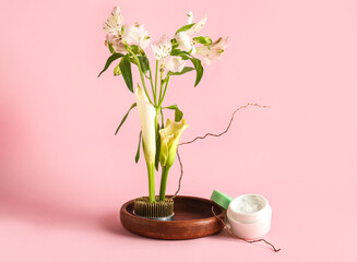 Jar of cream, stand and ikebana on pink background