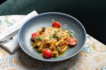 Italian Pasta penne with roasted tomato, sauce, mozzarella cheese on table.