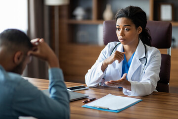 Black woman doctor having conversation with upset sick man patient