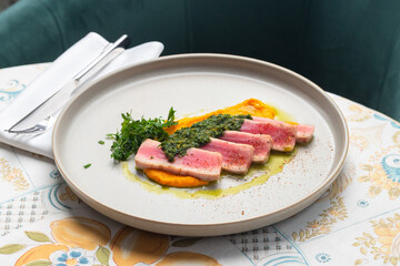 Juicy Tuna tagliata cut into slices on carrot puree. Beautiful serving, traditional Italian cuisine