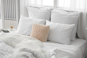 Big bed with cozy pillows in light room