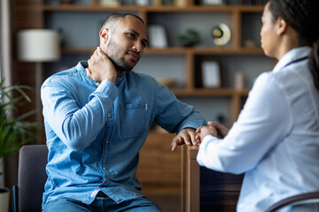 Young black man having apointment with doctor, touching neck