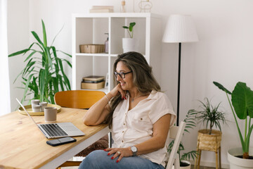 Smiling woman face timing via laptop from home