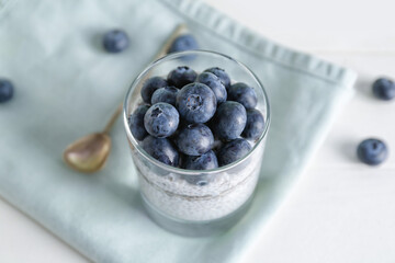Glass with delicious chia seed pudding and blueberry on table