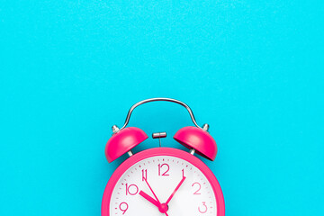 Close up of pink alarm clock over turquoise blue background with copy space. Photo of time...