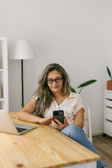 Portrait of adult businesswoman using phone at home 