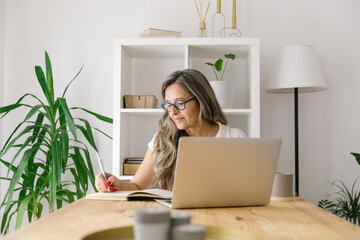 Female freelancer taking notes from browsing online