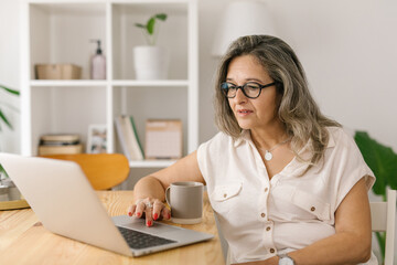 Mature woman sitting and browsing via computer