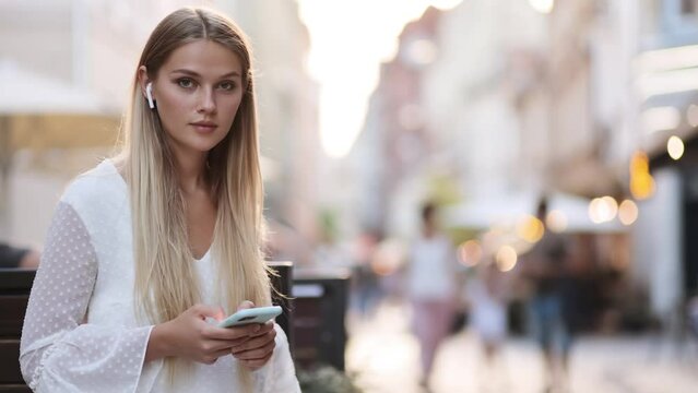 Cute beautiful woman using phone in urban evening city with natural light. Video with copy space for text. High quality 4k footage