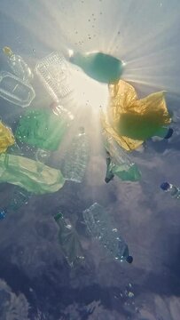 underwater image of how marine life sees the plastics floating on the surface of the water from below with the sun in the background