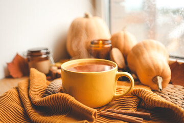 Autumn still life on the windowsill. Cup of tea, pumpkins and candle