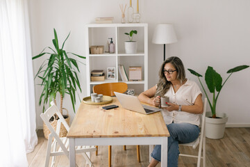 Woman holding cup of coffee and looking at the computer