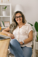 Cheerful portrait of adult businesswoman working from home, smiling and looking to the camera 