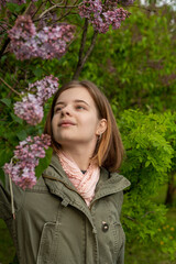 Portrait of a young teenage girl in the garden, a bush of blooming lilacs in the spring. High quality photo