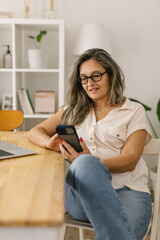 Obraz premium Boomer woman at home video chatting via cellphone.