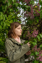 Portrait of a young teenage girl in the garden, a bush of blooming lilacs in the spring. High quality photo