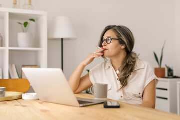 Mature woman sitting and smoking cigarette indoors