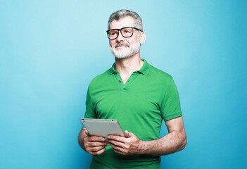 Photo of handsome mature man dressed green t-shirt and eyeglasses smiling typing modern device