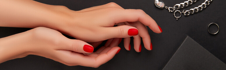 Manicured womans hands with accessories on black background. Halloween manicure, pedicure design...