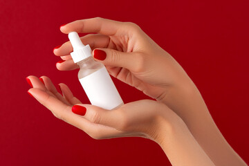 Womans hands holding dropper on red background