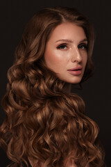 Naklejka premium Beautiful brown-haired girl with a perfectly curls hair, and classic make-up. Beauty face and hair.
