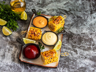 grilled yellow head corn with spices lime with white red orange sauce portion