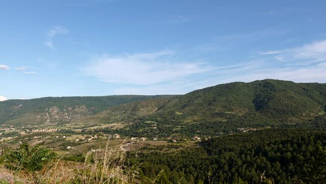 Time lapse shot of mountain Cr&ecirc;te des Bartes and valley Ravin de la C&ocirc;te des Furniers with Saint-Priest near Privas on a summer evening. After dusk the moon is rising behind a few clouds