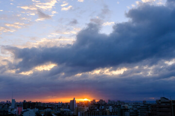 都市の夜明け。東の空に太陽が浮かび辺りをオレンジ色に染める。神戸市東灘区から芦屋市の高層マンション、大阪方面を臨む