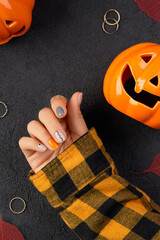 Womans hands with trendy minimal manicure on black background. Autumn halloween nail design