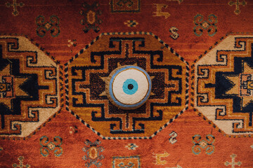 painted evil eye rock on colorful rug watching