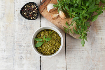 Homemade fresh herbal  Italian pesto sauce, green basil leaves, pine nuts, garlic, black pepper and olive oil served in bowl on wooden background