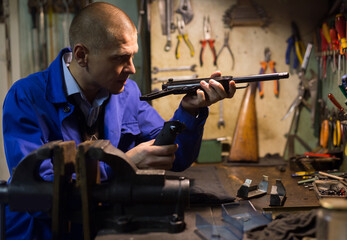 Professional gun repairman performing disassembly of sporting handgun, preparing firearms for...