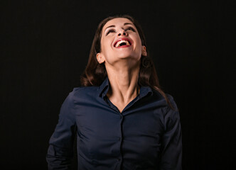 Beautiful funny toothy laughing business woman with wide open mouth looking up in blue shirt on black background with empty copy space for text. Closeup